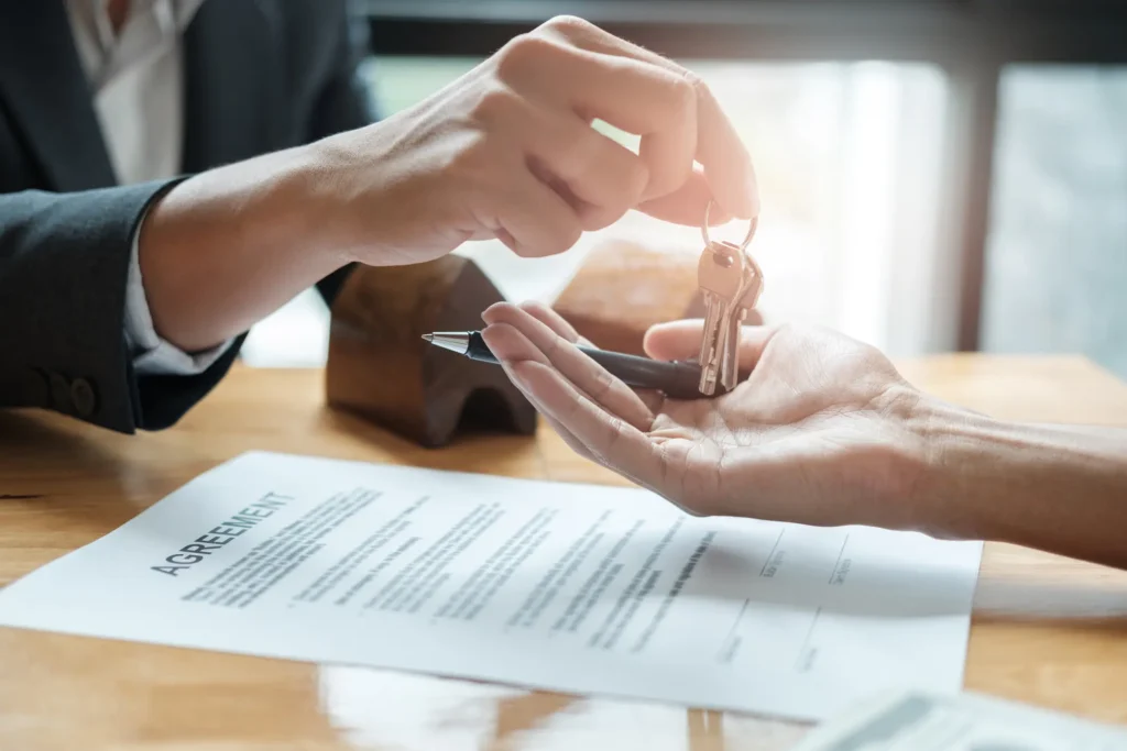 Estate agent giving house keys to man and sign agreement in office